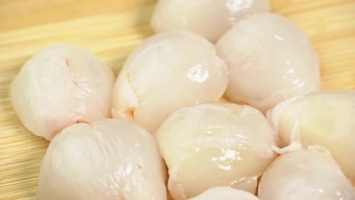 Frische geschälte Litschifrüchte ohne Schale rotieren in einer Glasschale im Makro. Litschibeeren
zur Herstellung
