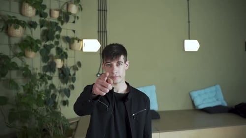 I need you! Young man European looking at camera pointing finger at camera smiling. Shakes head yes