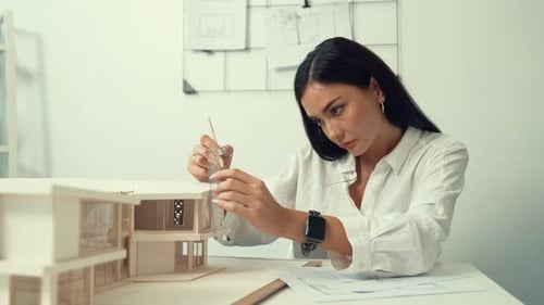 Architect using ruler to measure house model at modern office. Immaculate.