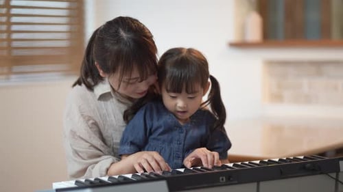 Mother Teaching Child to Play Keyboard at Home