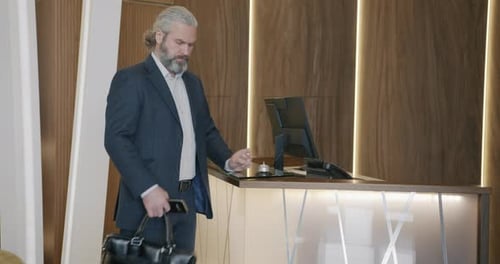 Well-Dressed Man Rings Bell at Reception Desk