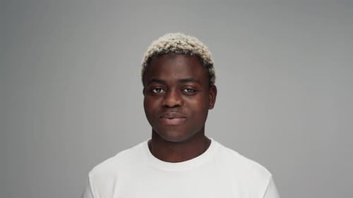 Smiling Man in White Shirt Against Gray Background