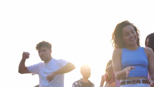 Group of Young Adults Dancing Outdoors in Sunlight