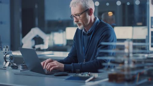Professioneller Elektronikkonstrukteur mit Brille arbeitet am Laptop im Forschungslabor, Tu