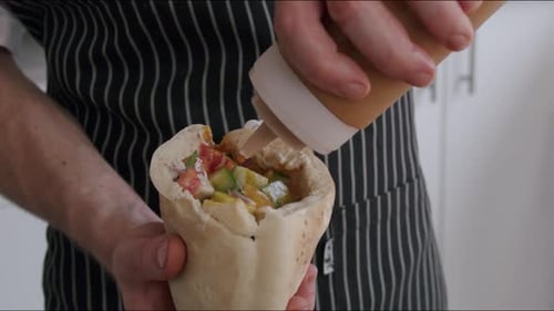 Chef Saucing Pita Bread With Fresh Vegetables