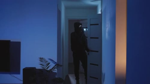 Figure with Flashlight Walks Down Dark Home Hallway