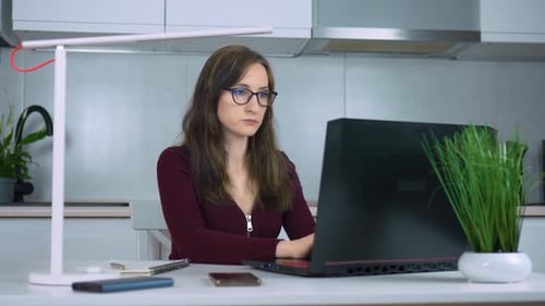 Female in Protective Glasses Professional Typing on Laptop Sits at Home Office Desk Businesswoman