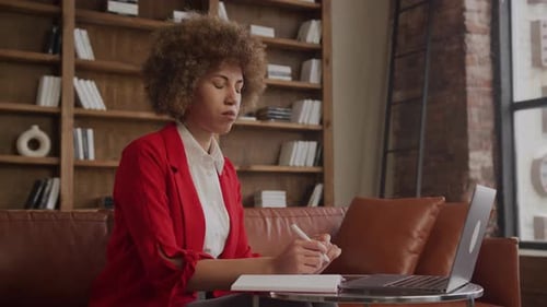 Businesswoman Making Notes While Watching Educational Course