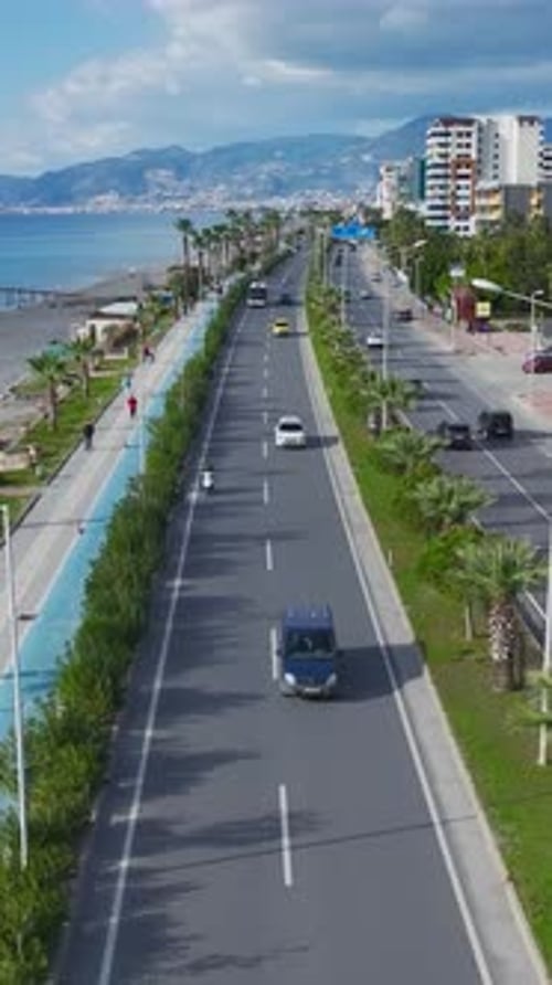Vertikale Videowagen fahren entlang einer Küstenstraße mit Meereswellen und malerischer Küste in der