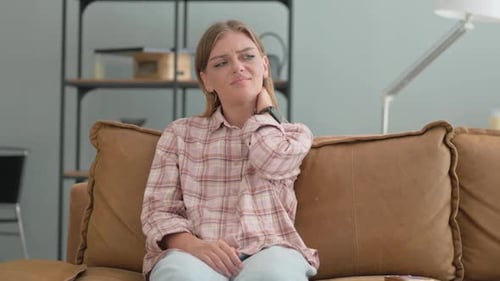 Young Woman Massaging Sore Neck on Couch