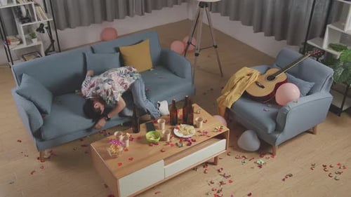 Vue de dessus d'un homme asiatique ivre se réveille après avoir dormi sur un canapé dans la salle de fête de la maison
