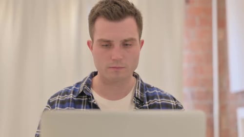 Close up of Young Man with Headache Working on Laptop
