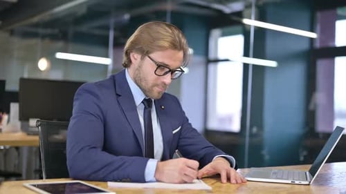 The Businessman writing Documents on Office Desk