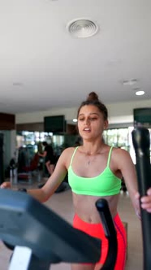 Woman Works Out on Elliptical Machine in Gym