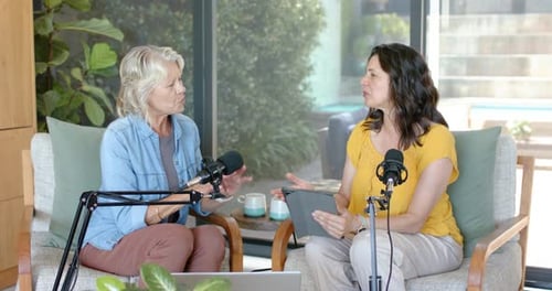 Diverse female hosts using tablet guiding chat, left host counting points for recording with mics