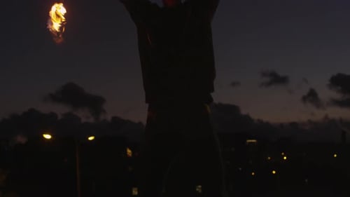 Man Spins Flaming Batons at Night in City