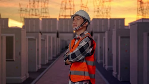 Side View Of Asian Male Engineer Crossing His Arms with High Voltage Power