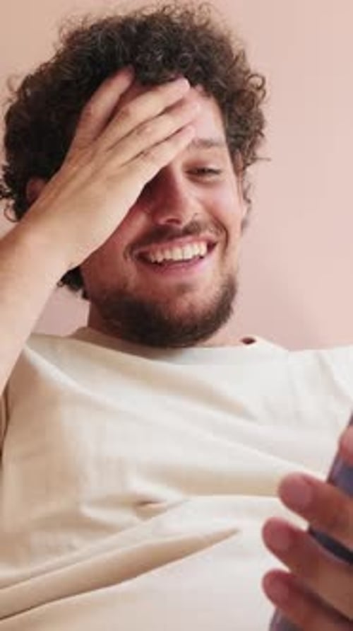 Man Smiles While Looking at His Smartphone