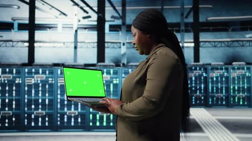 Developer in Data Center Using Green Screen Laptop to Upgrade Systems