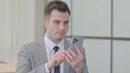 Young Adult in Suit Using Smartphone in Office