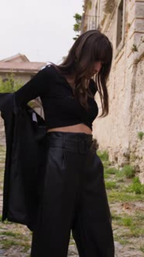 Girl Takes Off Her Black Jacket In A Street Of A Village