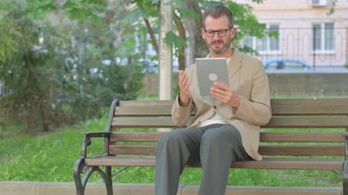 Man Using Tablet on Park Bench