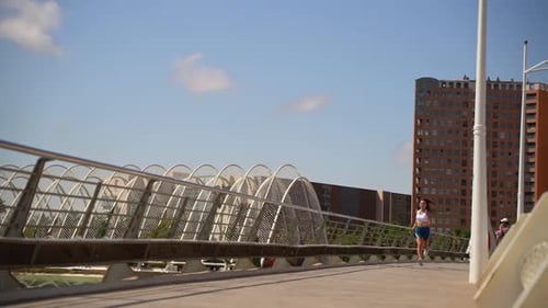 Woman Jogging On City Bridge In Sunny Day
