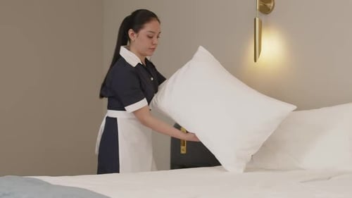 Latin Chambermaid Making Bed in Cozy Hotel Room