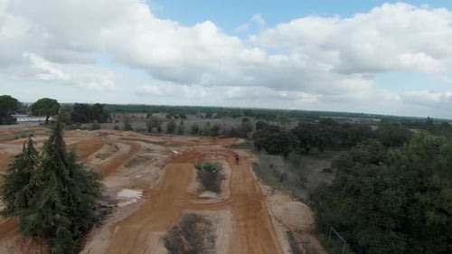 Aerial view of motocross rider on dirt track surrounded by trees