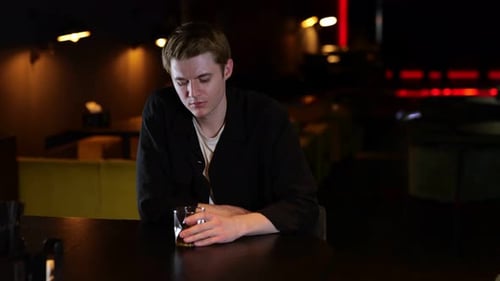 Young Man Drinking Whiskey While Sitting in a Restaurant in the Evening and Feeling Lonely Lifestyle