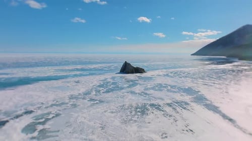 Winter ice and rocky islet on Lake Baikal under clear blue sky, Russia
