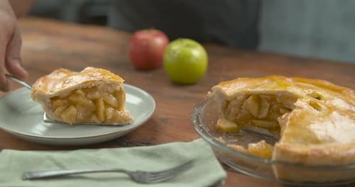 Slow motion close up of a slice of apple pie being served on a wood table