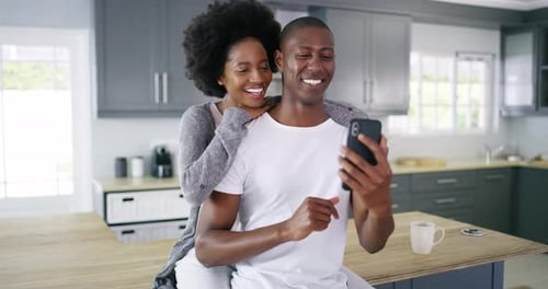 Loving Couple Laughing at Phone in Modern Kitchen
