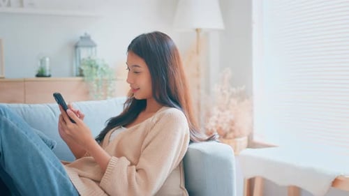 Young Woman Relaxing on Couch with Smartphone