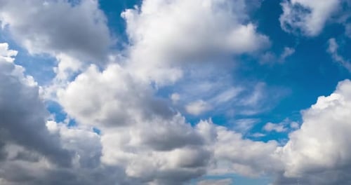 Flying below white soft cumulus clouds. Beautiful blue sky at backdrop. Low angle view. Timelapse.