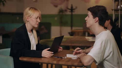 Un chico y una chica se divierten hablando mientras están sentados en una mesa en un café Una chica se sienta en una mesa