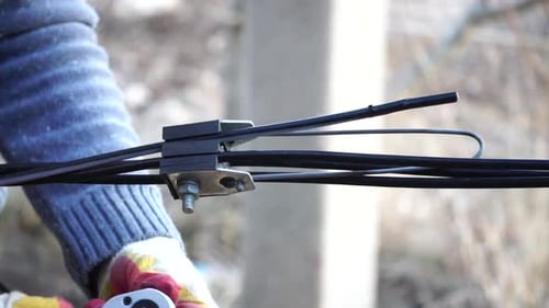 Man Repairs Black Cables with Wrench