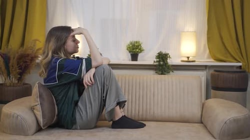 Sad Woman Sitting on Couch in Bright Room