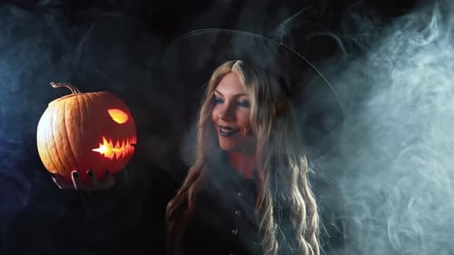 Smiling Witch Holds Glowing Jack-O-Lantern