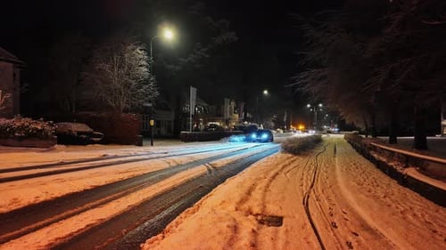 Car driving over a snow and ice covered road on a cold winter night.