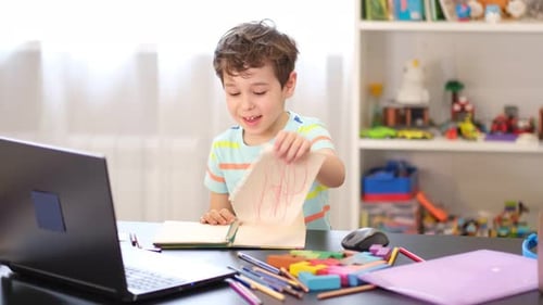 Happy Boy Drawing at Desk and Crumpling Paper