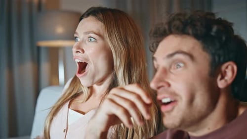 Couple Laughing and Watching Television Indoors Together