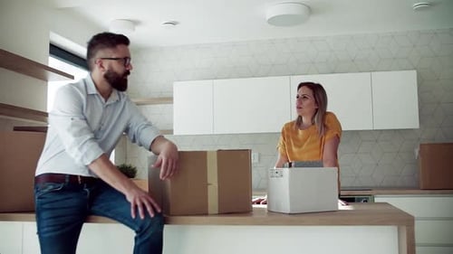 Couple in new home stands talking amongst moving boxes