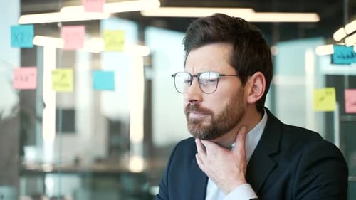 Stressed Man in Office Rubbing Sore Throat