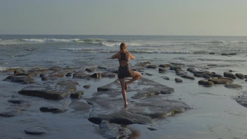 Back View of Sporty Slim Blonde Girl Doing Yoga on Sunny Day Outdoors on Beach