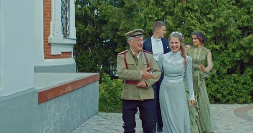 Happy Women in Beautiful Historical Dresses Walk Near the Mansion with Men in Military Uniforms and