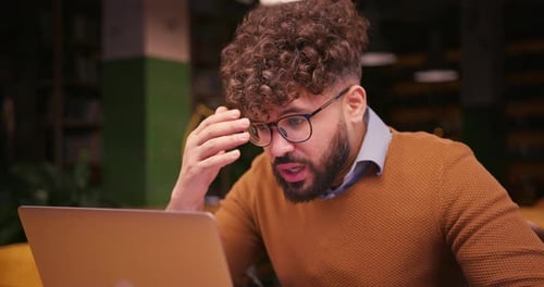 Sad Male Middle Eastern Worker Programmer Working on Laptop in Modern Coworking
