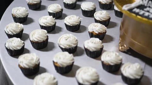 Several cupcakes with white cream on a table at wedding celebration party in hotel.