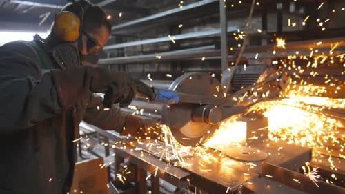 Craftsman with Circular Saw Sawing Steel in Workshop