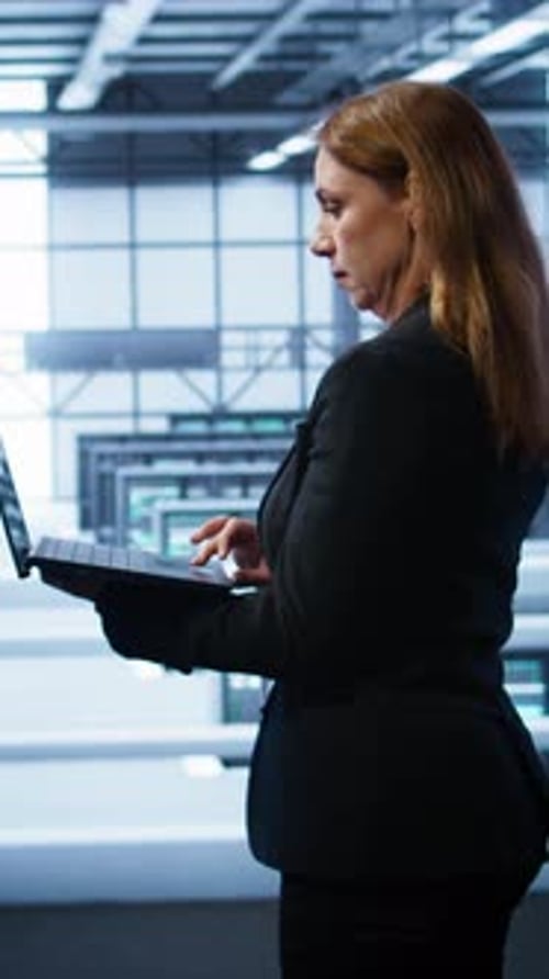 Vertical Video IT Specialist in Server Hub Monitoring Server Infrastructure Using Notebook